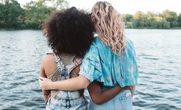 two-girl-friends-standing-hugging-water-outside